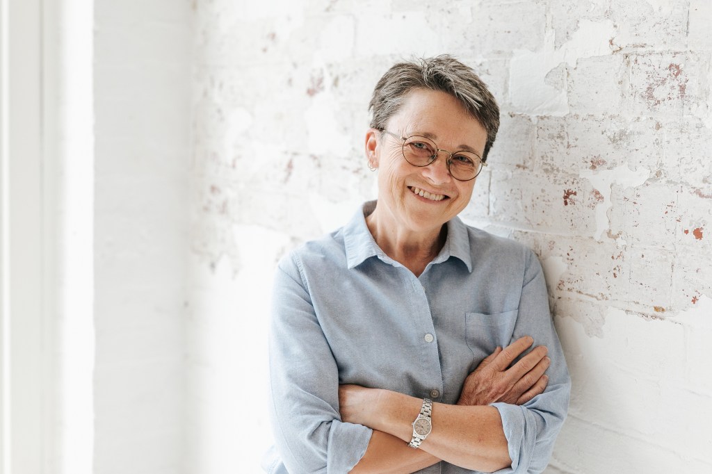 Portrait of Kelly in pale blue shirt, leaning against a wall